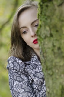 Thoughtful young woman standing behind a tree