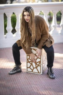 Woman shot hands playing percussion with a Flamenco box sitting on top of it in a park