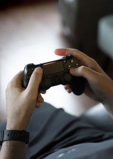 High angle view of an adult man's hands holding a joystick while playing a video game on a console