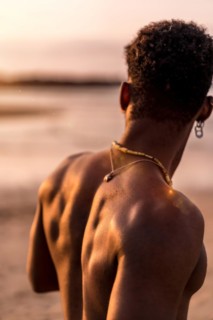 Back of muscular black ethnic man on summer vacation by the sea feeling free