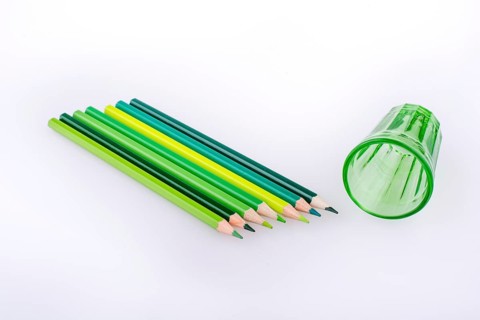 Color Pencils and a green glass on a white background