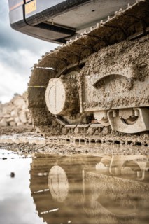 Tracked excavator in dirt with puddle