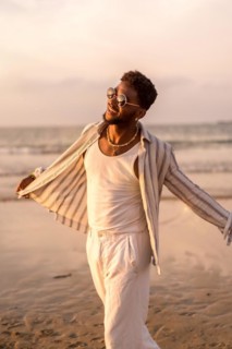 Portrait of attractive black ethnic man enjoying summer vacation by the sea feeling free