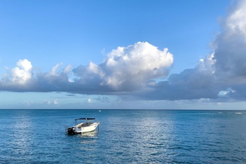 Small motorboat sports boat with awning lies at anchor in smooth sea no waves in bay