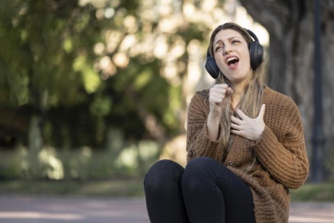 Blonde woman sitting on the street listening to music
