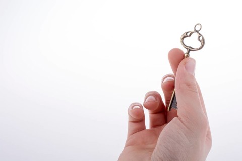 Hand holding a retro styled metal key on a white background
