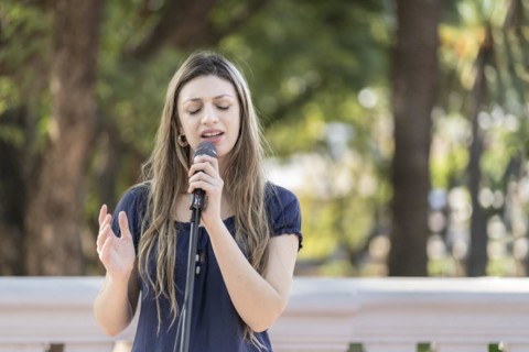 Young blonde woman singing in the street. Singer performing in the street