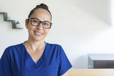 Woman in glasses wears a blue uniform looks at the camera smiling. Close up and copy space. Medical concept