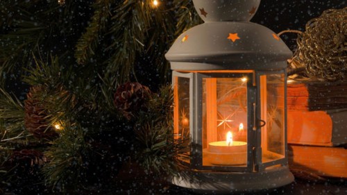 White lantern with a burning candle. Books
