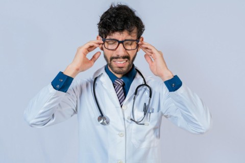 Young Doctor suffering with headache isolated. Doctor with migraine holding his head