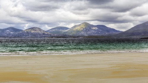 View from the sandy Luskentyre Beach over the sea bay East Loch Tarbert to the mountains