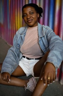 Portrait of Young African American Woman sitting on the floor on a colorful metal wall