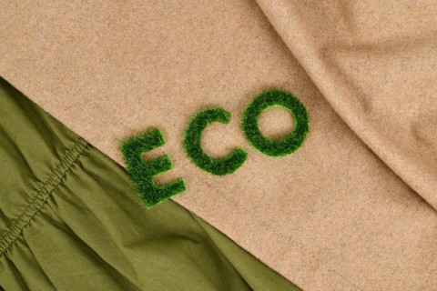 Concept for environmental friendly produced clothing with text 'ECO' made out of grass on textiles