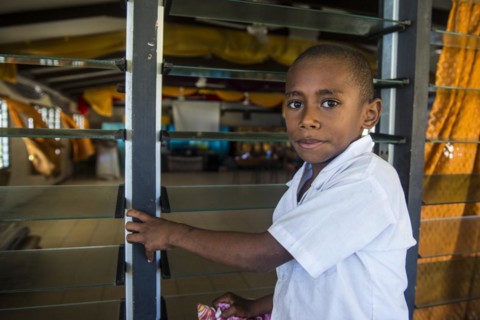 School boy cleaning the windows of their school