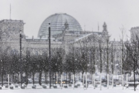 The Reichstag building is silhouetted against snowfall in the government district in Berlin