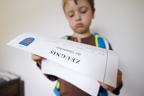 Symbolic photo on the subject of report cards in primary school. A boy poses with a report card. Berlin