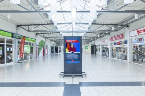 An information board shows a message with Angela Merkel