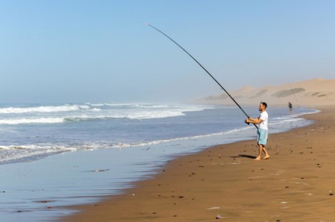 Fisherman standing by Atlantic Ocean