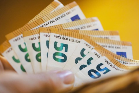 Symbolic photo on the subject of cash. 50 euro banknotes are held in one hand. Berlin