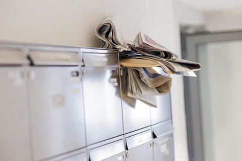 Newspapers and letters stuck in the opening of a crowded letterbox. Berlin