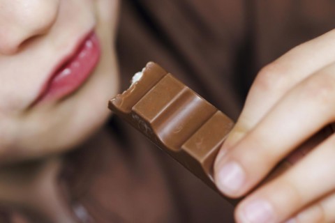 Symbolic photo on the subject of eating chocolate. A boy takes a bite from a chocolate bar. Berlin