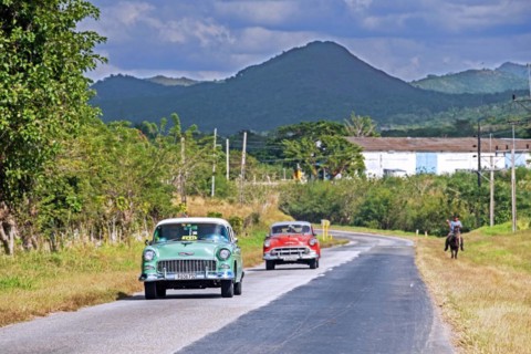 Vintage Chevrolet taxi and red classic American car driving along Circuito Sur