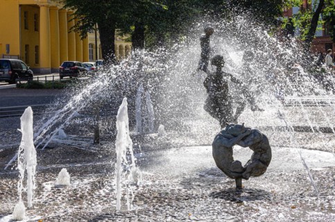 Urban scene at the fountain of joie de vivre on the Universitaetsplatz in the backlight