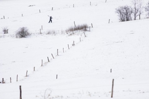 A boy carries skis up a slope in Koenigshain
