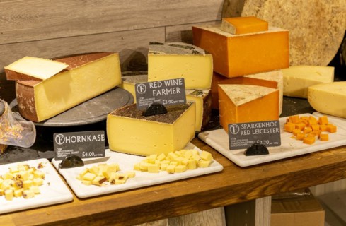 Variety of cheeses on display in cheese room of farm shop