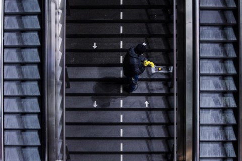 A cleaner wipes a staircase marked with arrows for the respective walking directions