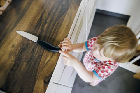 Symbol photo on the subject of dangers in the home. A small child reaches for a knife in the kitchen at home. Berlin