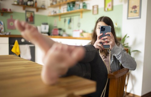 Subject: Girl sitting with feet on the table in the living room using a mobile phone