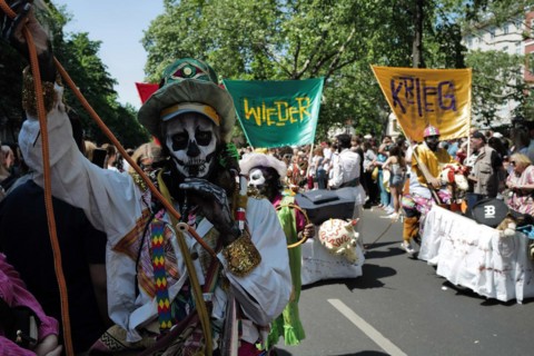 An anti-war participant entertains the crowd before the start of the Carnival of Cultures in Berlin. The event passed off in glorious sunshine this afternoon as Berlin residents enjoyed the good Whits...