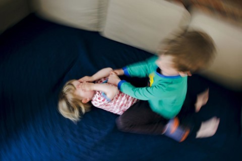 Symbolic photo on the subject of quarrels between siblings. A two-year-old girl and a five-year-old boy fight on a couch at home. Berlin