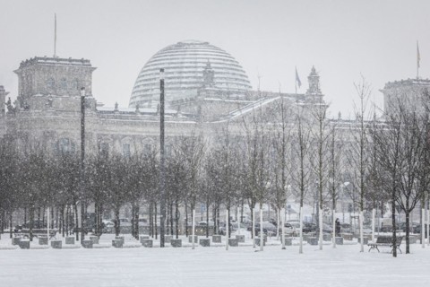 The Reichstag building is silhouetted against snowfall in the government district in Berlin