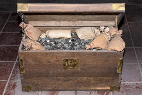 Wooden chest filled with coins and money bags