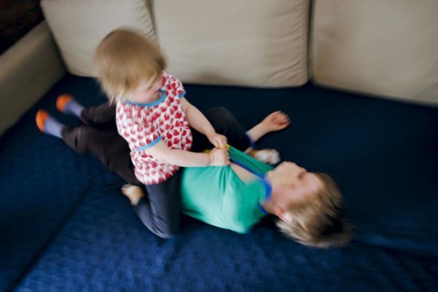 Symbolic photo on the subject of quarrels between siblings. A two-year-old girl and a five-year-old boy fight on a couch at home. Berlin