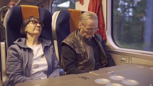 An elderly couple ride the train early in the morning and sleep