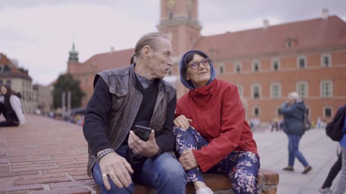 Elderly couple of tourists are sitting and talking in the historic center of an old European city