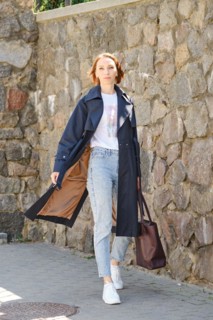 Elegant middle aged woman walks city street wearing blue trench coat