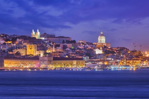 View of Lisbon over Tagus river with passing ferry boat from Almada with ferry in evening twilight