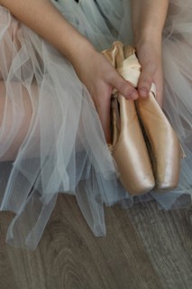 Legs of girl dancing ballet with tulle skirt and pink shoes different dance steps wooden floor and white background with copy space