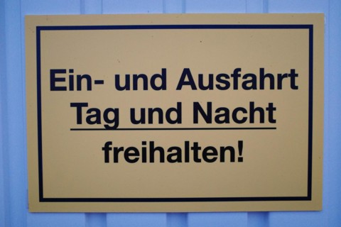 Sign with inscription Keep entrance and exit clear day and night!