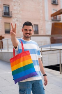 Portrait of gay man with a rainbow lgbt bag in the city