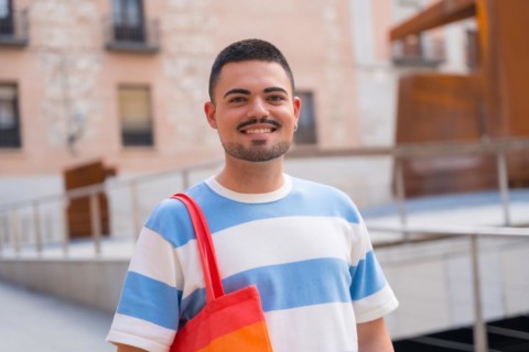 Portrait of smiling gay man with rainbow lgbt bag in the city