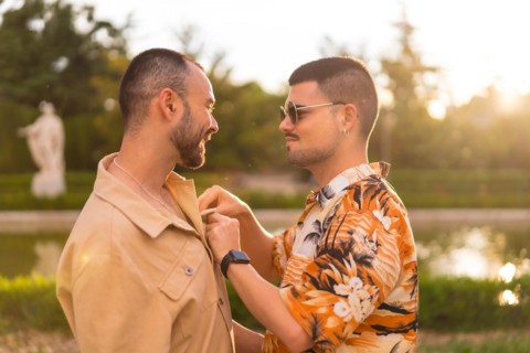 Homosexual couple embracing giving each other a kiss looking at the sunset in a park in the city