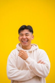Portrait of a handsome South Korean Asian man in basic clothes smiling isolated over yellow background