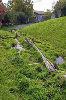 Spring with wooden water pipe in green meadow