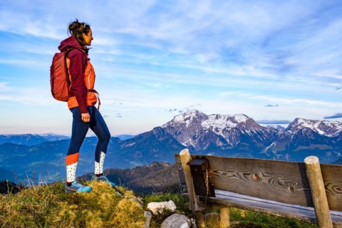Mountaineer next to a wooden bench enjoying the view towards Hoher Göll