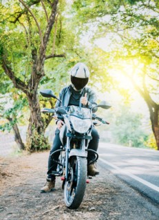 Motorcyclist in safety helmet with thumb up on the road